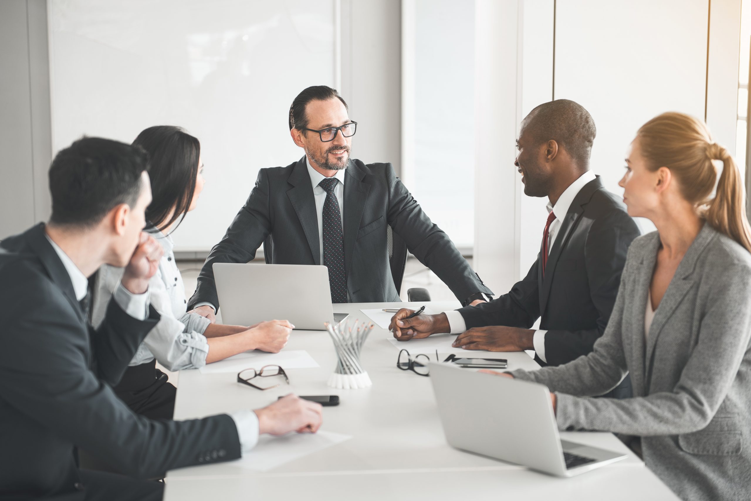 Employees,Sitting,At,Table,In,The,Office,And,Listening,To Executive team meeting in Olympia, Washington