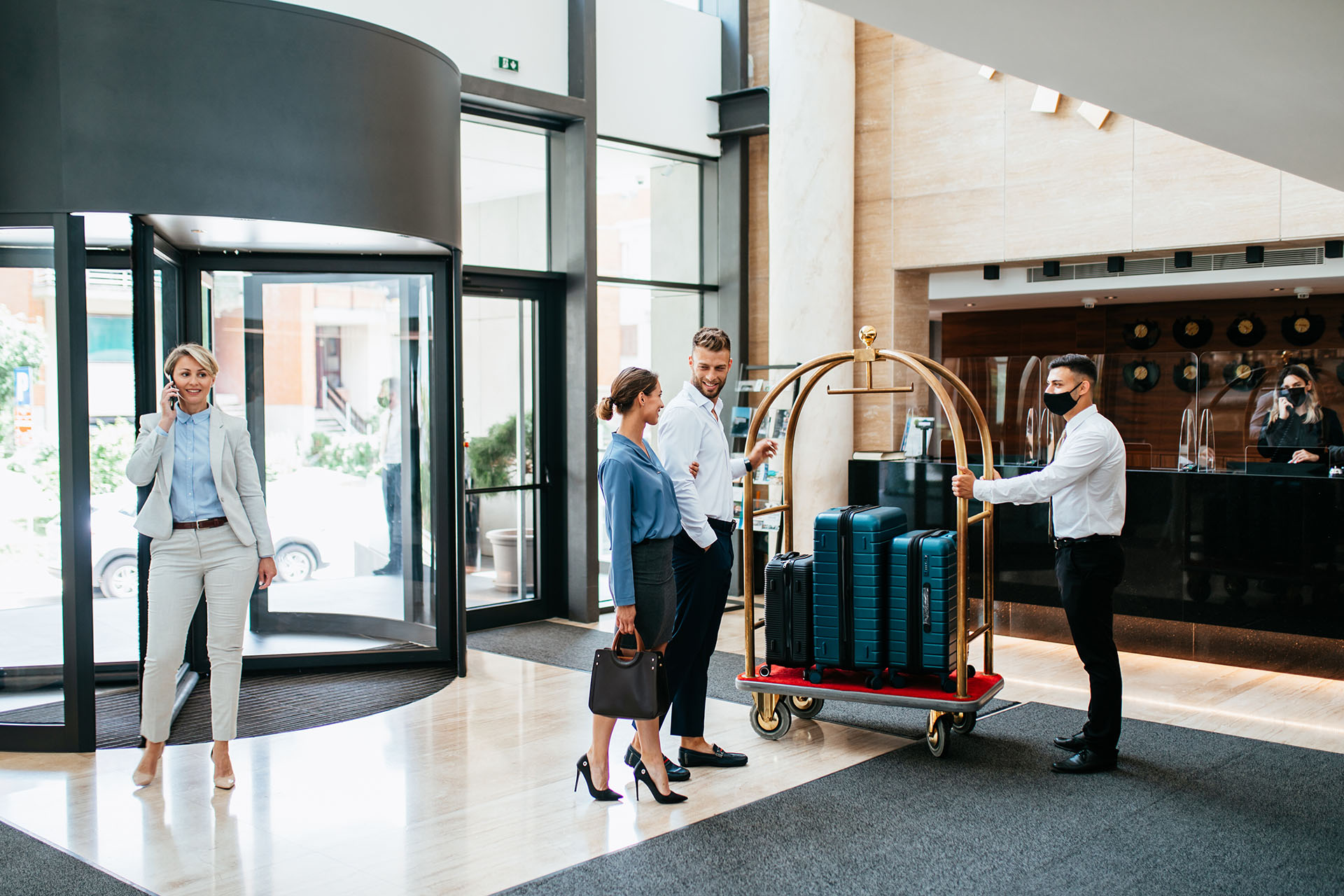 Bellhops moving luggage for a business woman in a hotel lobby